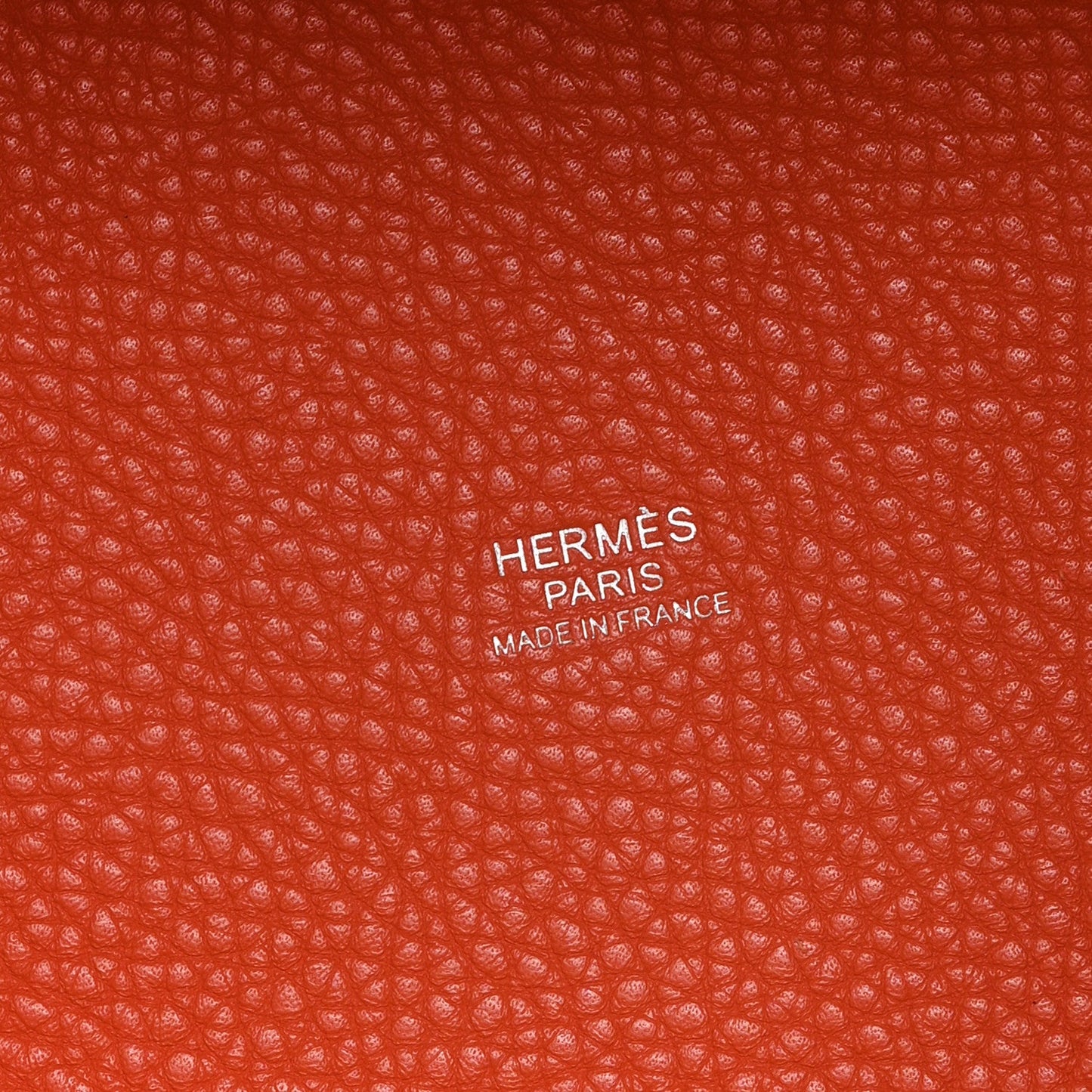 Orange pebbled leather handbag with HERMS PARIS embossed branding label