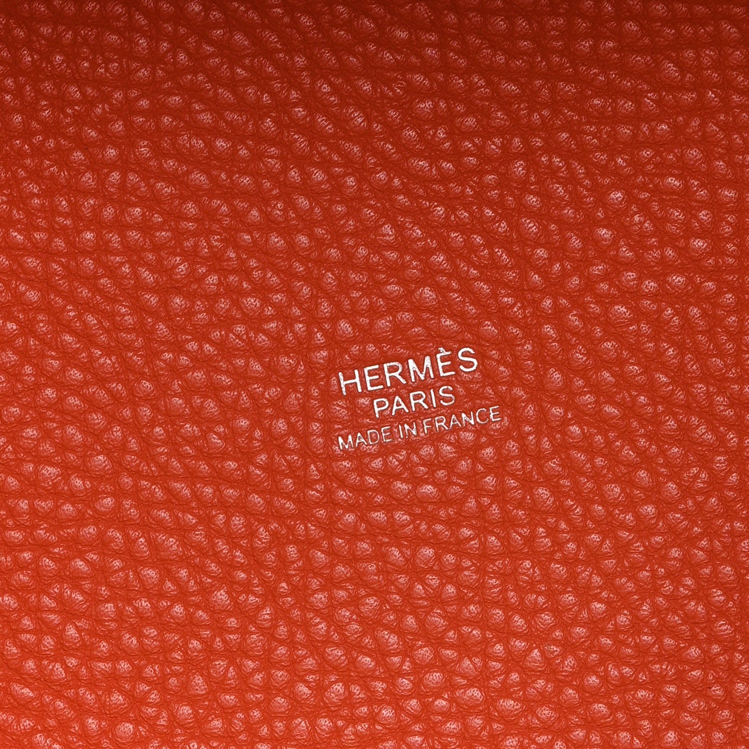 Orange pebbled leather handbag with HERMS PARIS embossed branding label