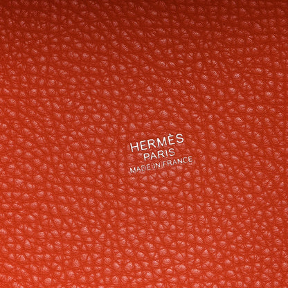 Orange pebbled leather handbag with HERMS PARIS embossed branding label