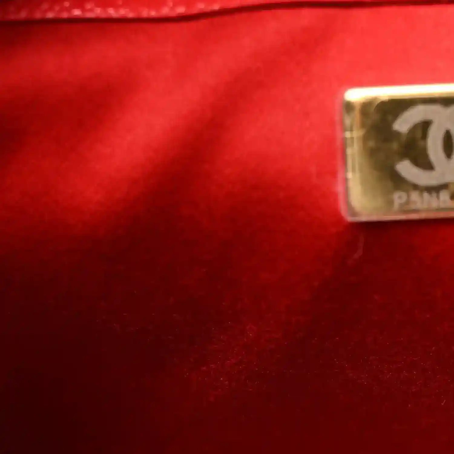 Metal CC logo plaque on burgundy leather handbag.