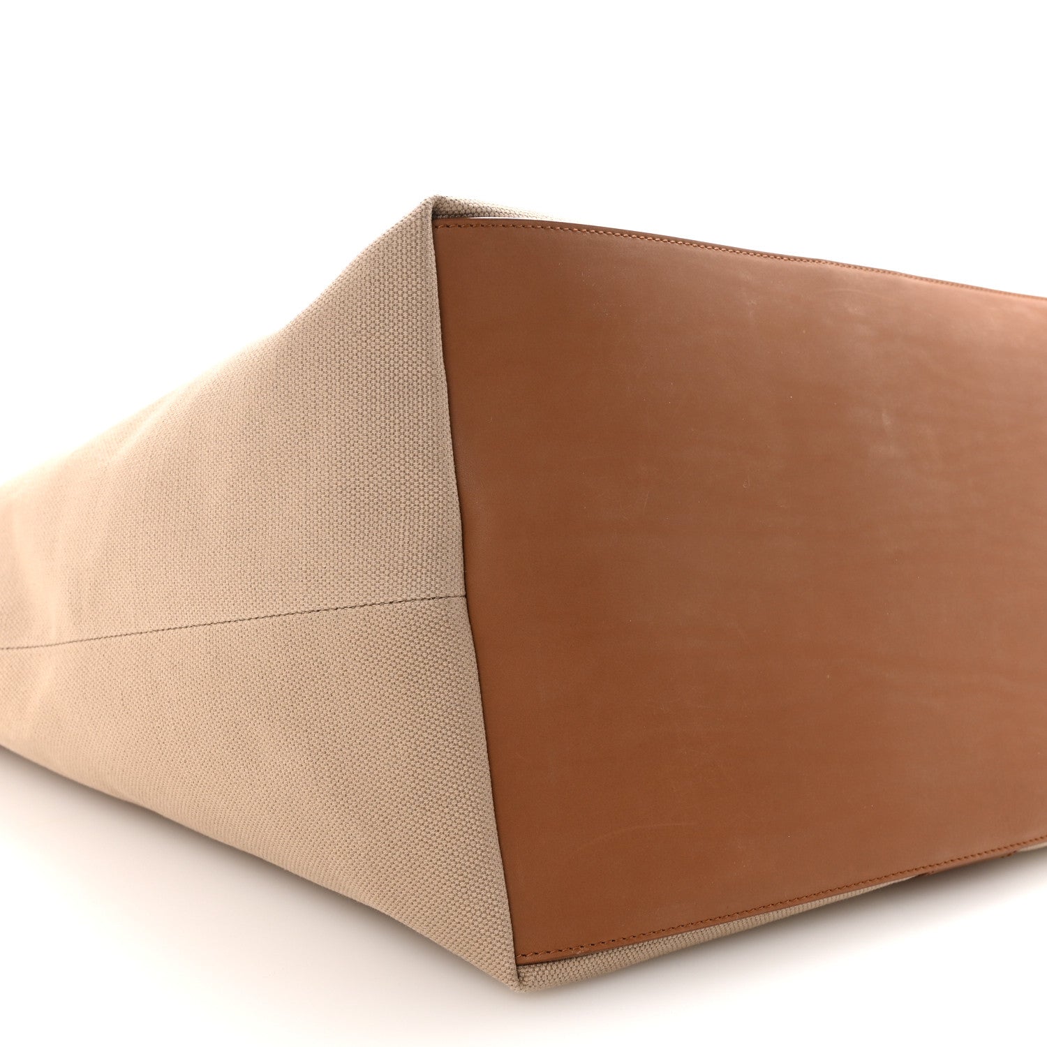 Tan canvas tote base with brown leather panel, close-up angled