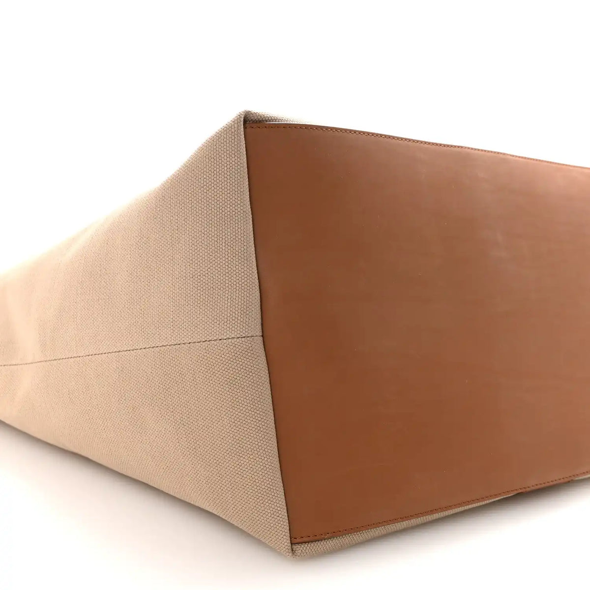 Tan canvas tote base with brown leather panel, close-up angled