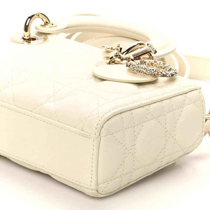 Small white quilted handbag with top flap, chain strap, and gold-tone bow accent