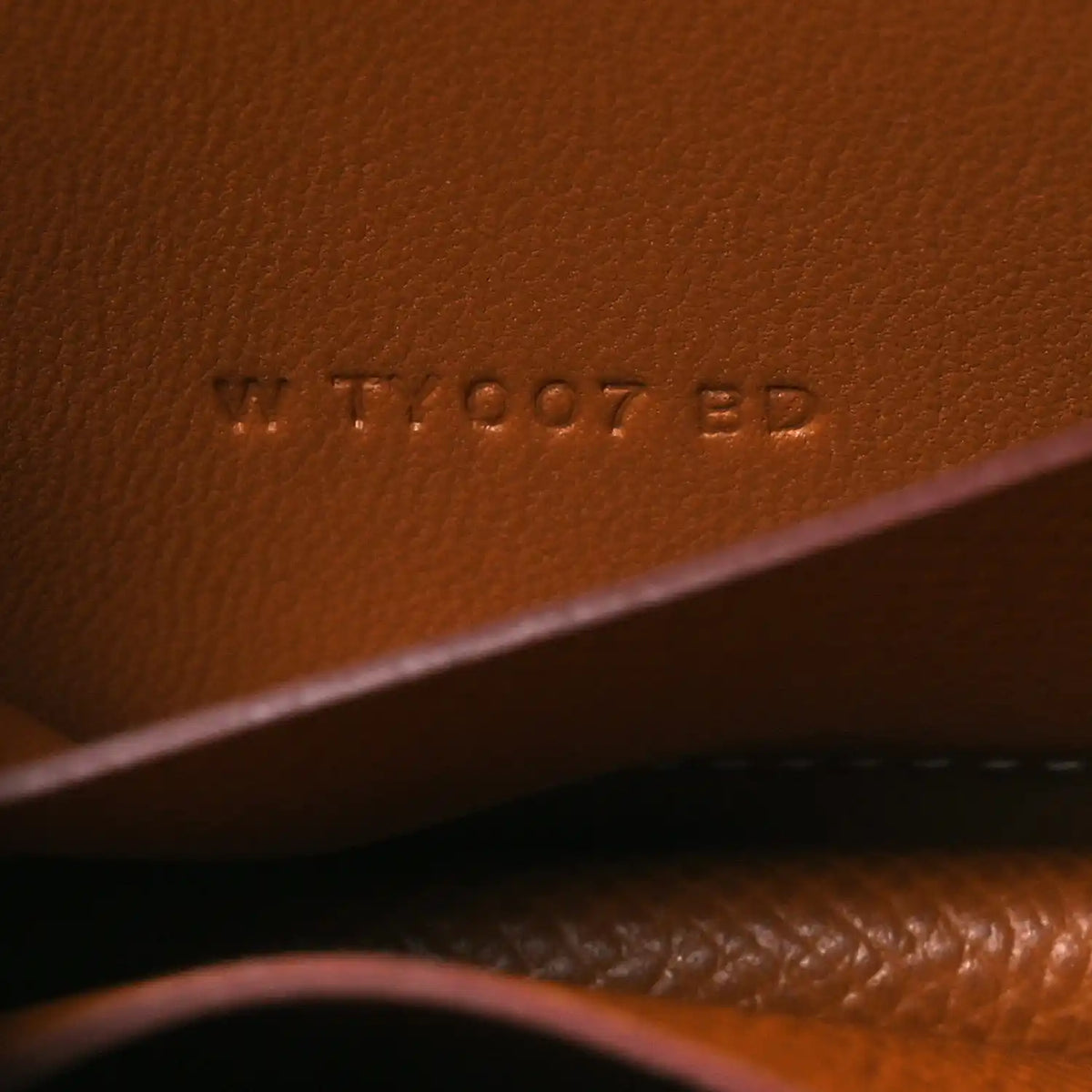 Constance slim wallet embossed serial marking on tan leather surface