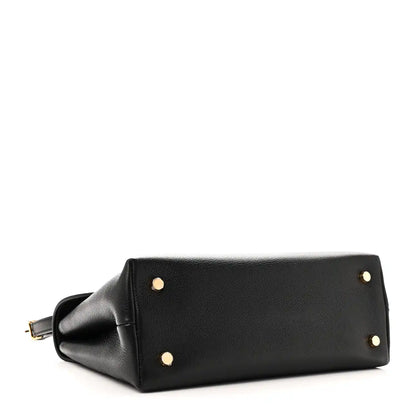 Black leather handbag bottom corner with gold studs and attached strap loop