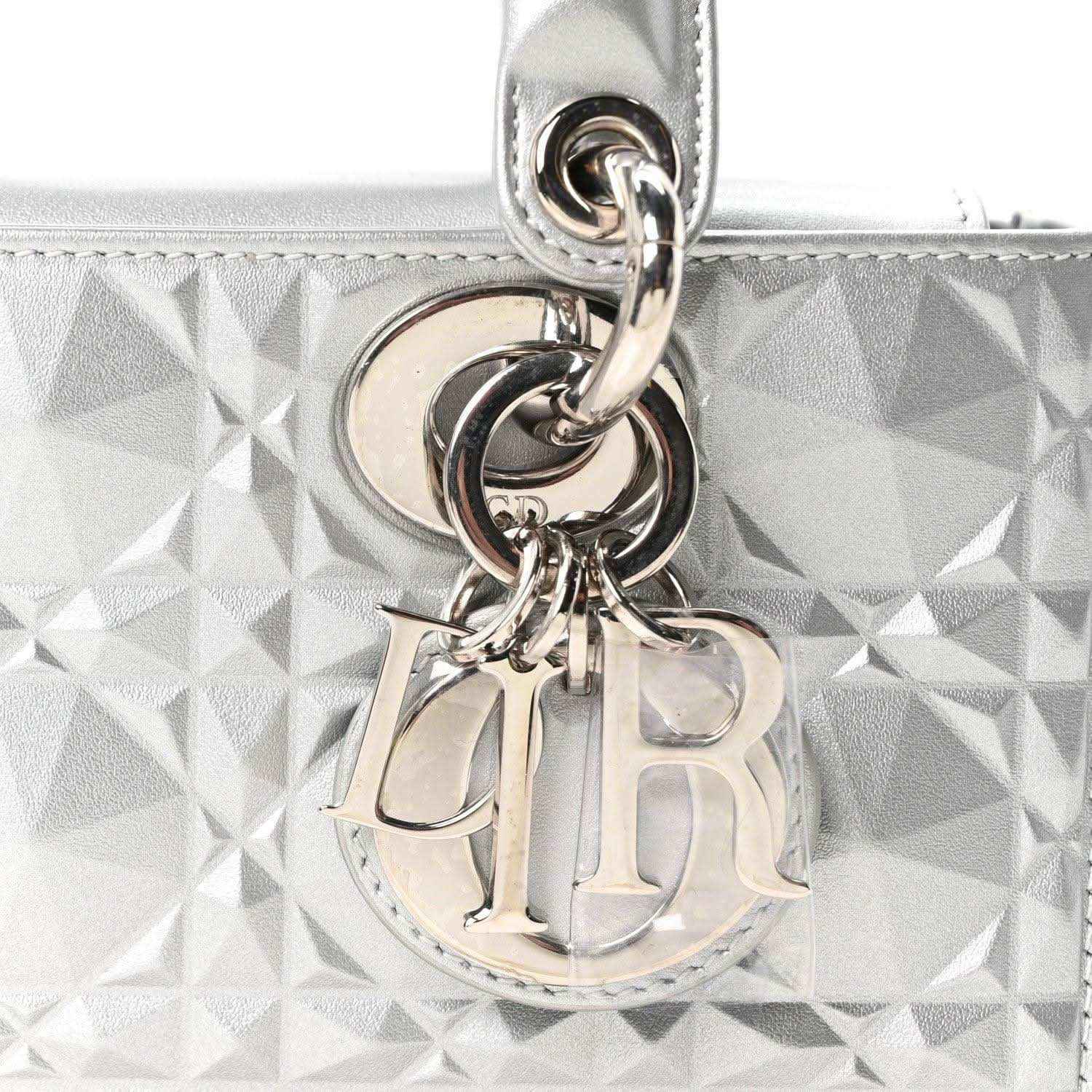 Metal DIOR charm and ring hardware on metallic silver geometric textured handbag.
