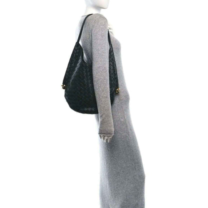 Dark green woven hobo bag on shoulder with top handle and gold zipper pull