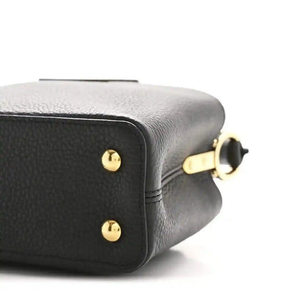 Black leather mini handbag close-up of side panel with gold ring hardware