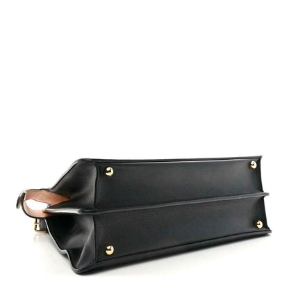 Black satchel with structured top frame, gold-tone feet, and side handle