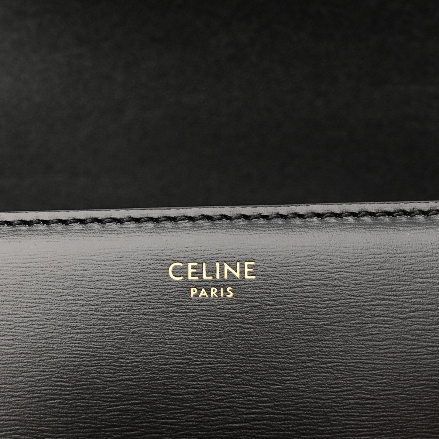 Black leather bag lining with 'CELINE PARIS' embossed text and stitched edge.