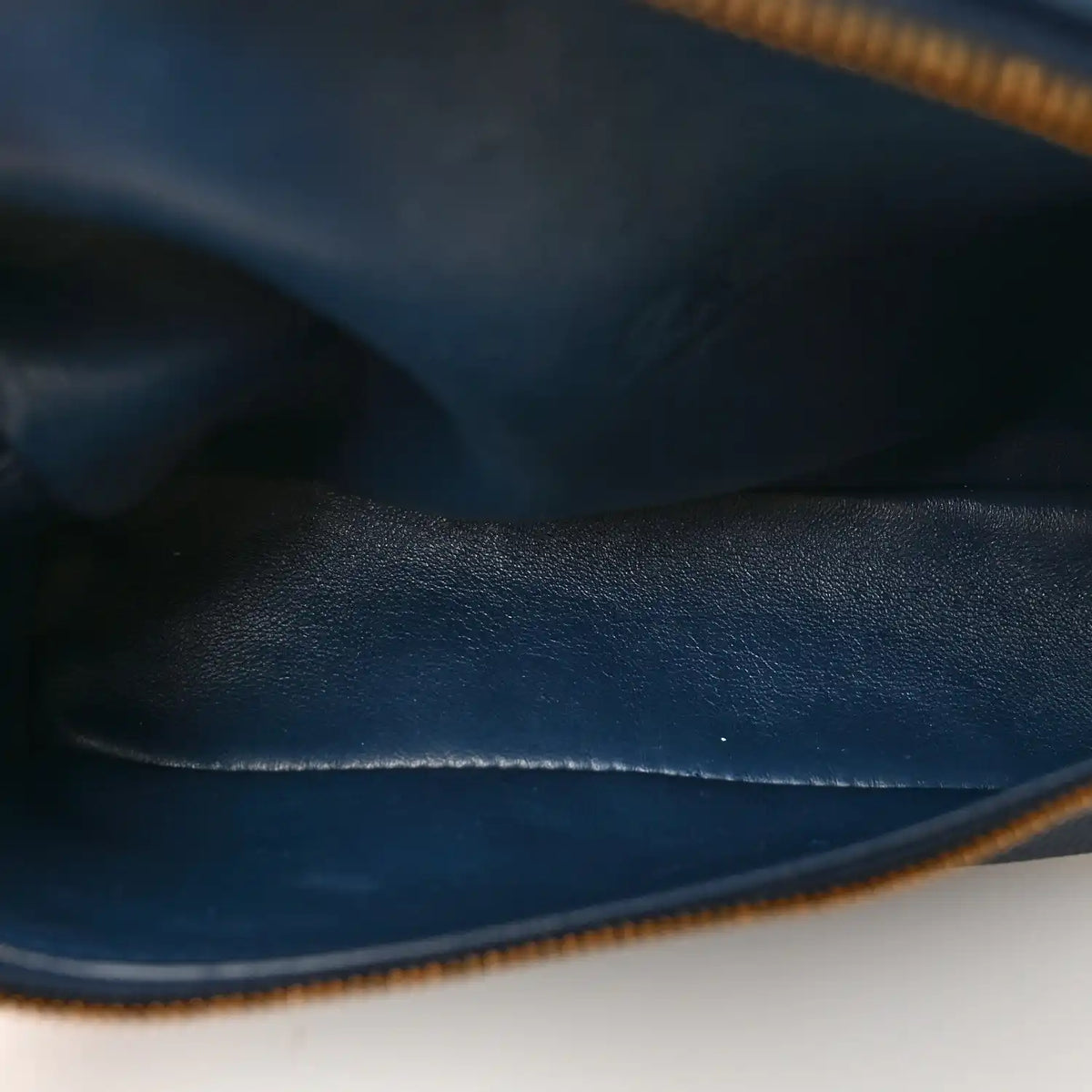 Navy grained calfskin pouch with gold zipper edge and close-up stitching