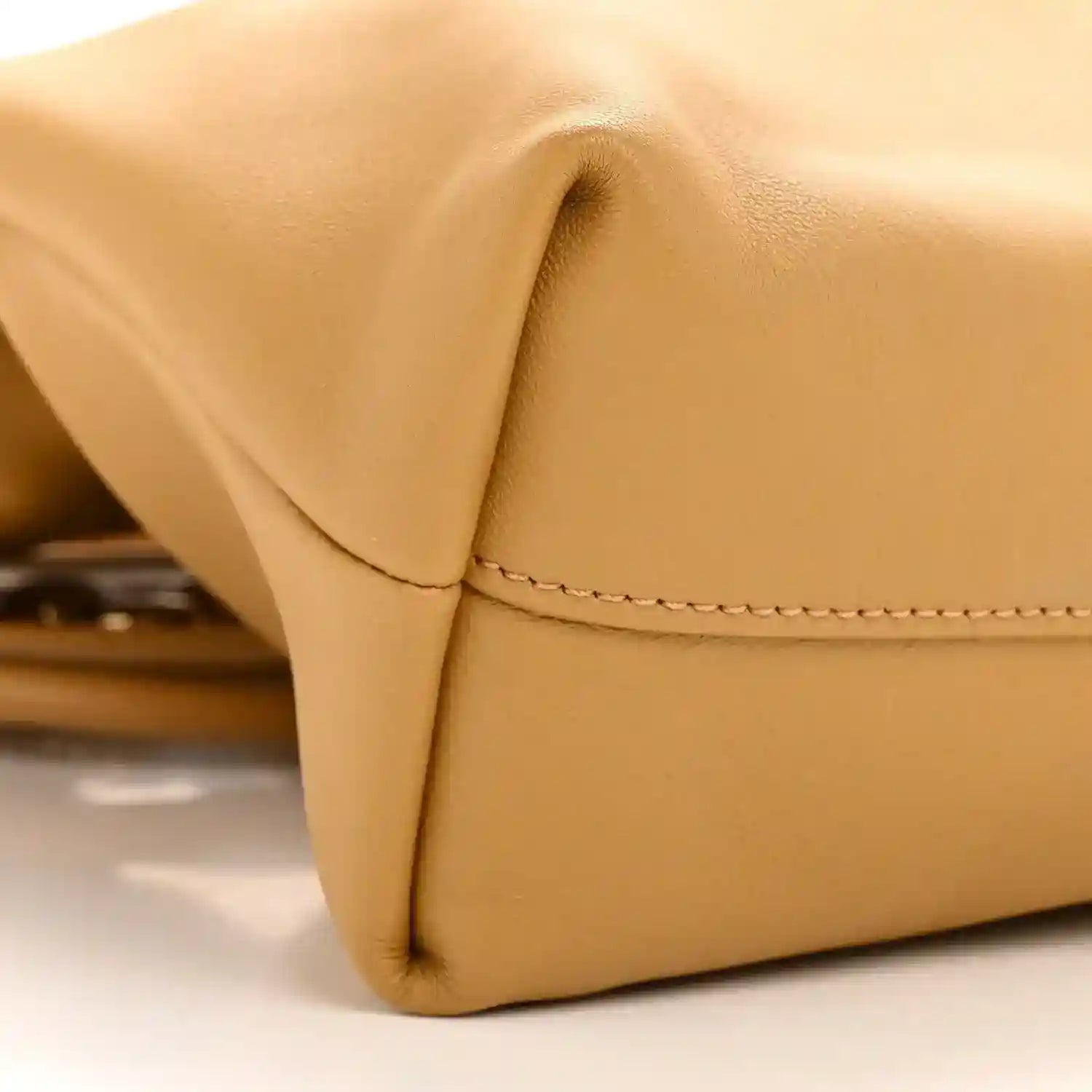 Tan leather clutch corner with smooth flap and visible edge stitching