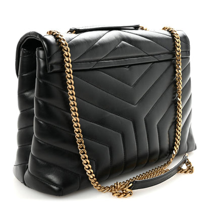 Black quilted satchel with gold chain strap and top handle.
