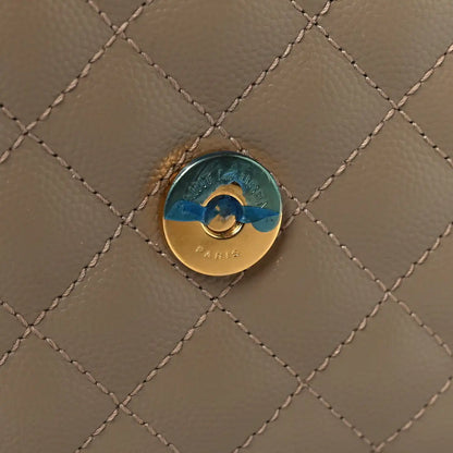 Round metal snap button on dusty grey quilted satchel front