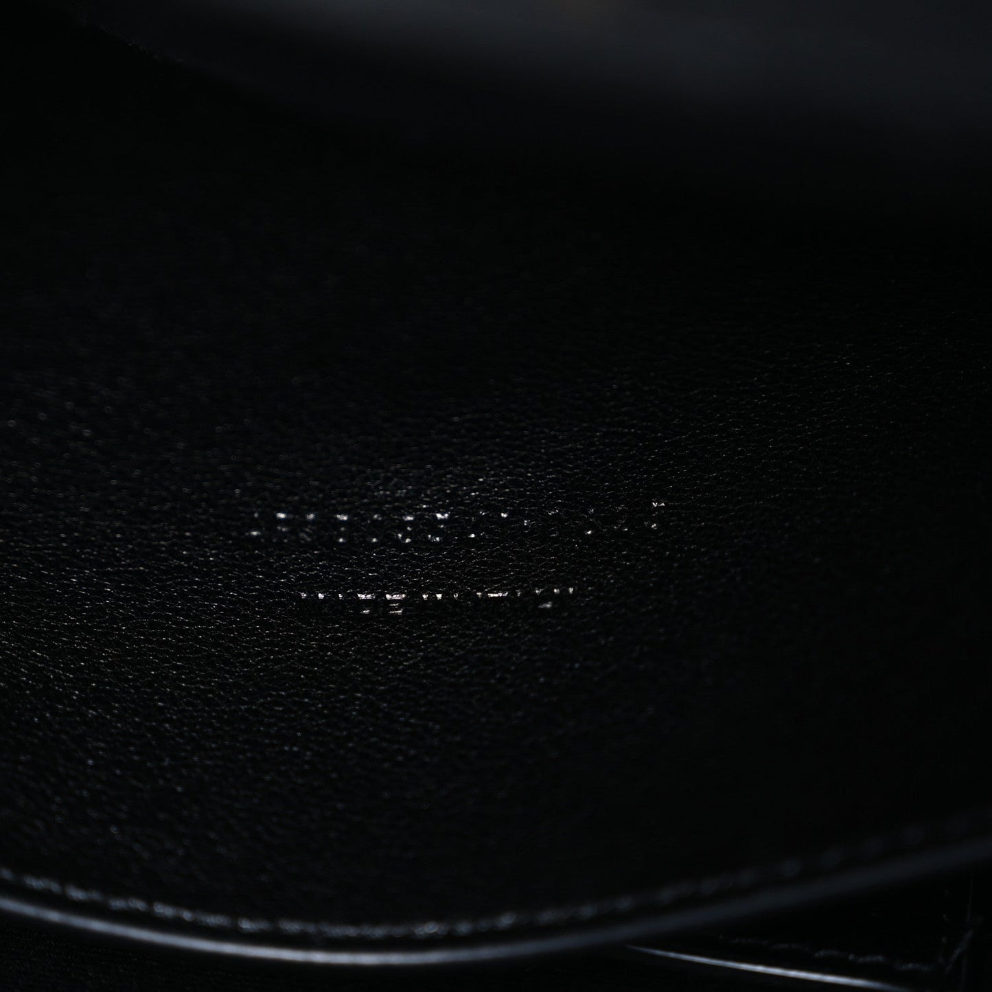 Black leather bag corner with smooth edge and textured grain close-up
