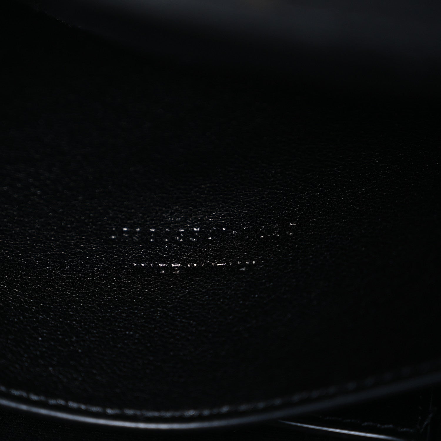 Black leather bag corner with smooth edge and textured grain close-up