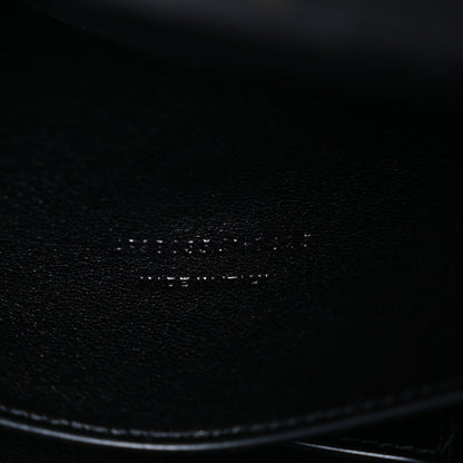 Black leather bag corner with smooth edge and textured grain close-up