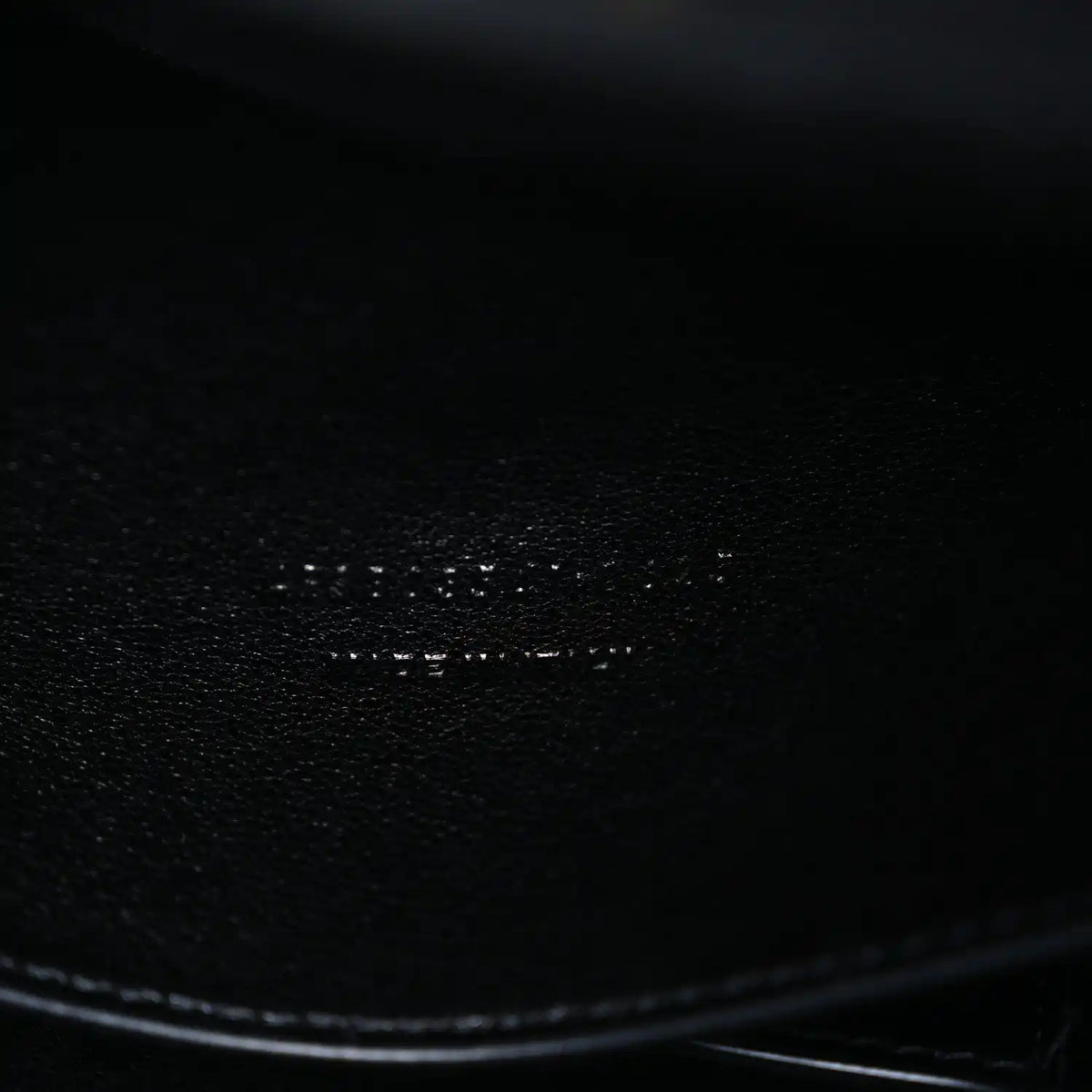 Black leather bag corner with smooth edge and textured grain close-up