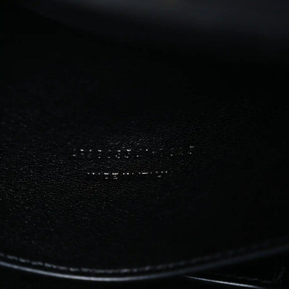 Black leather bag corner with smooth edge and textured grain close-up
