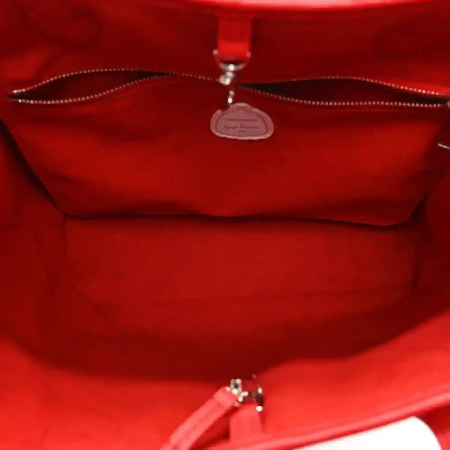 Red interior view of tote bag with center zip and small logo medallion