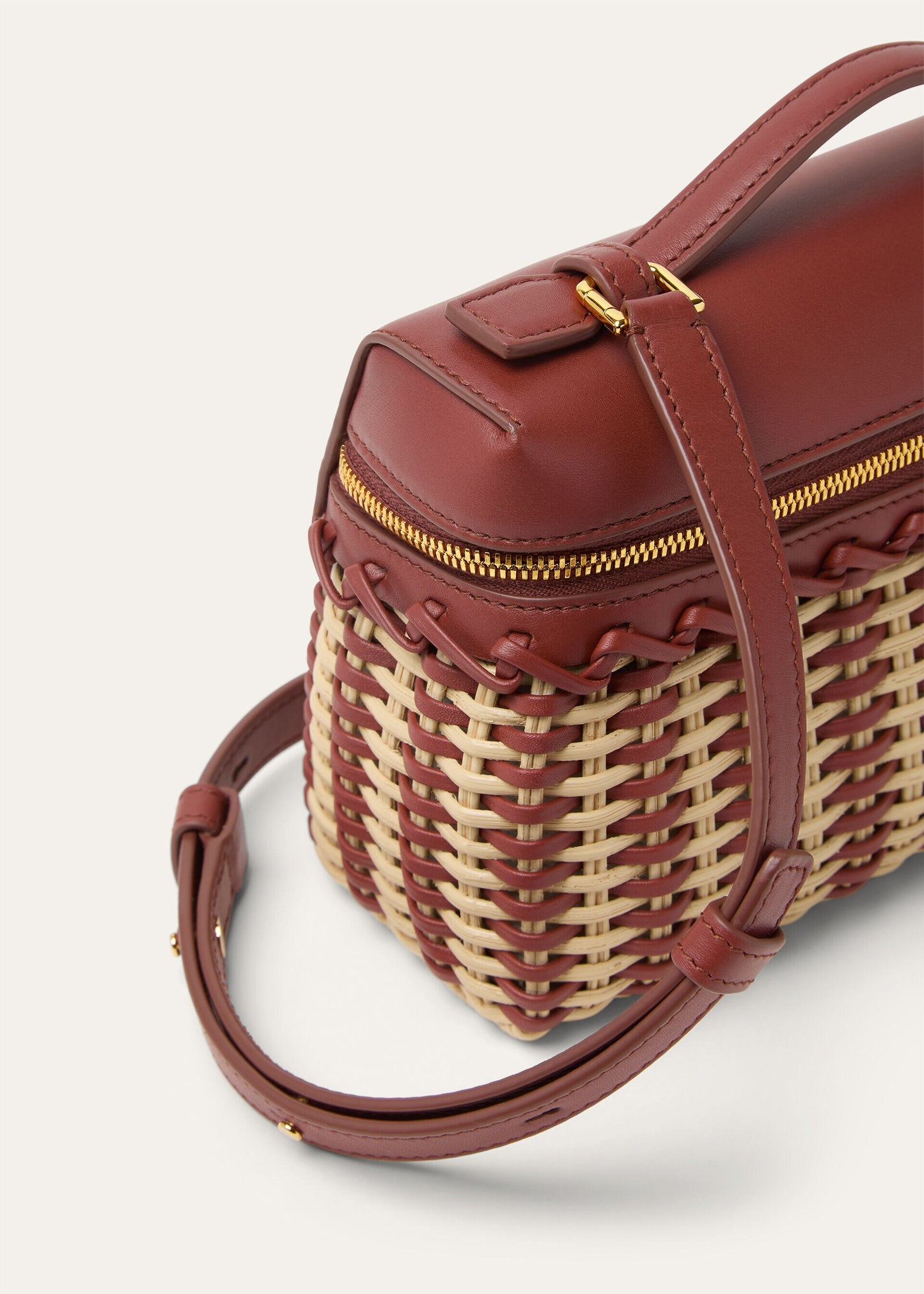Wicker and calfskin crossbody pouch with adjustable strap, gold zipper and front pocket.