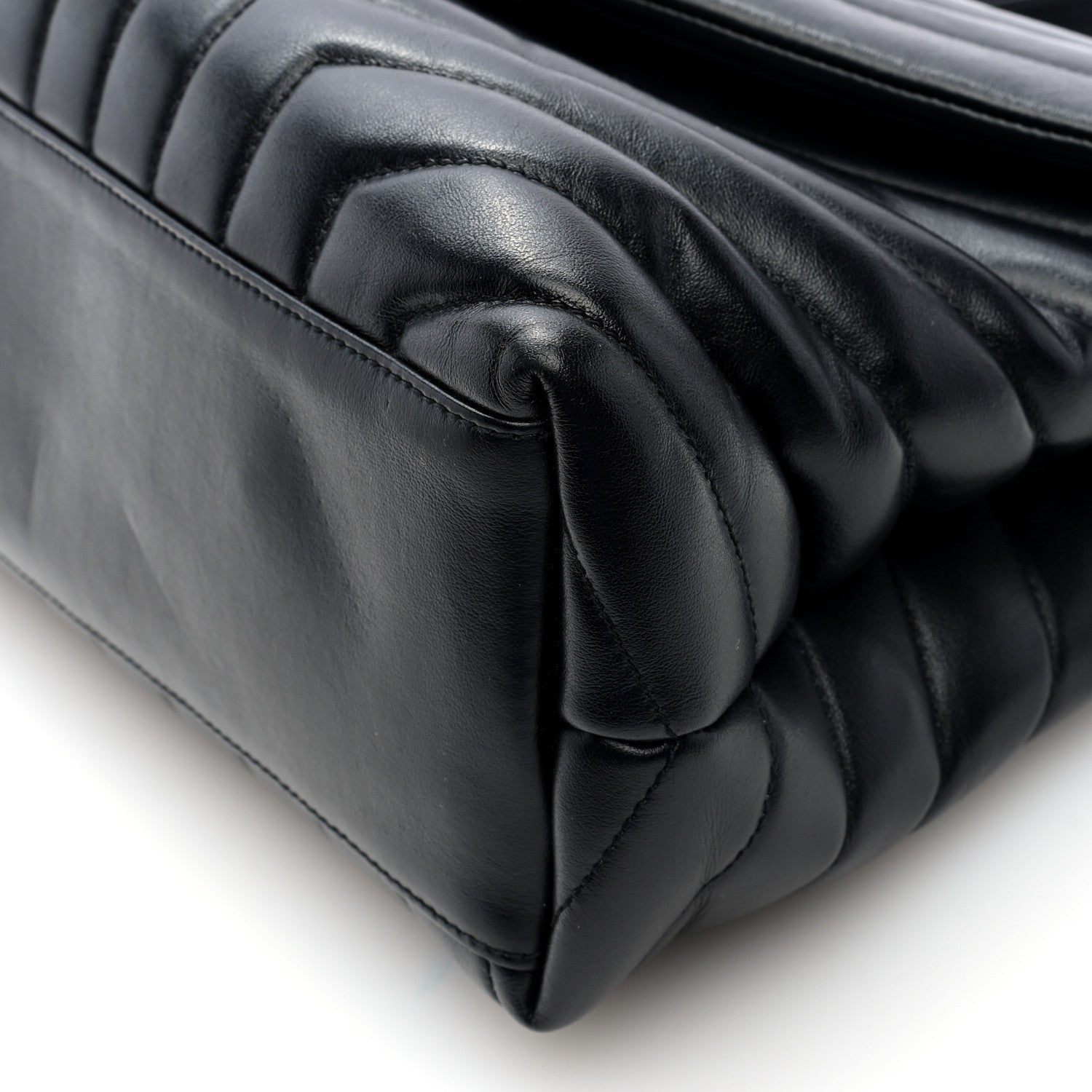 Black quilted satchel close-up of stitched handle and padded leather edge