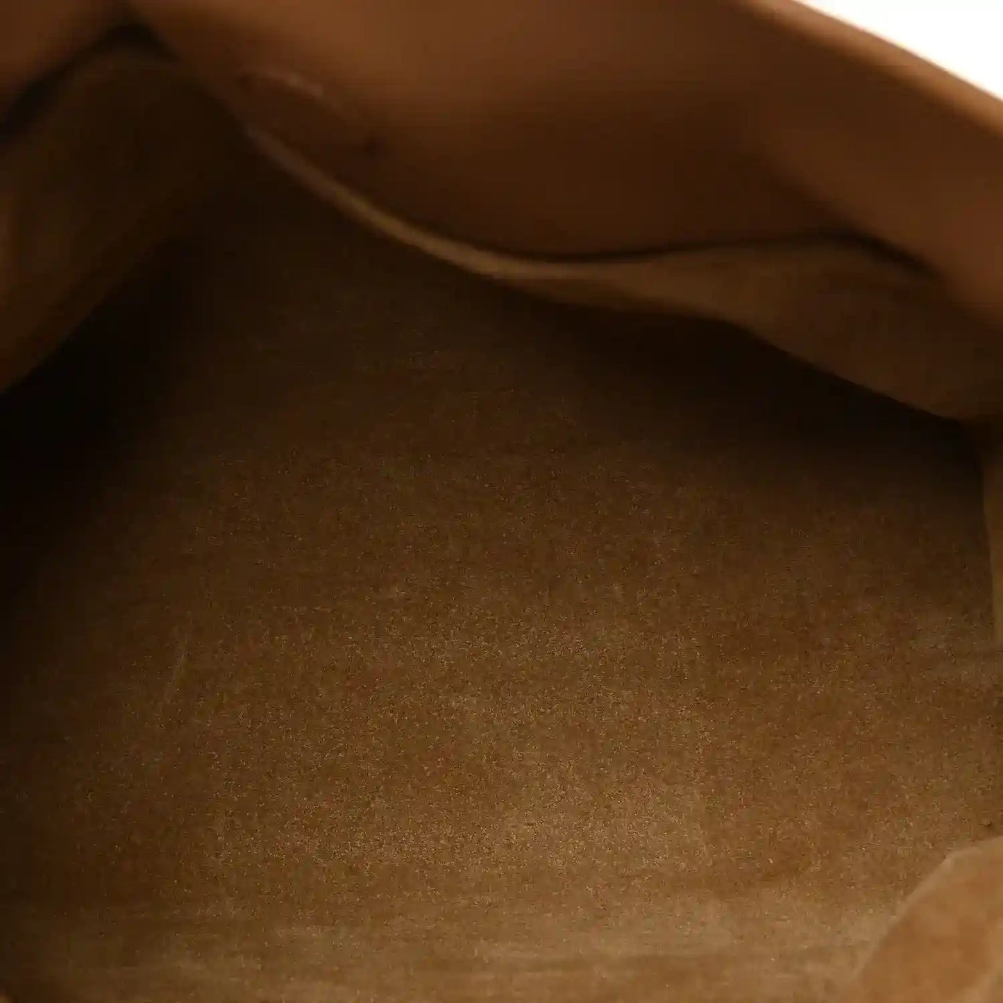 Tan leather mini clutch interior close-up with smooth fabric lining.