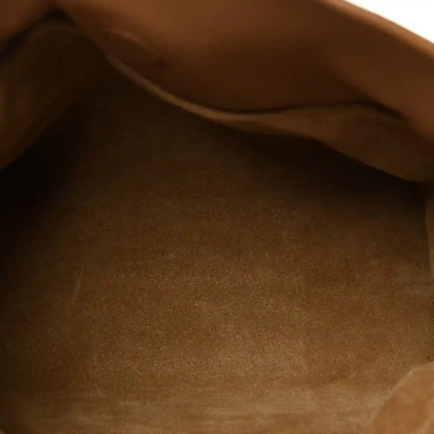 Tan leather mini clutch interior close-up with smooth fabric lining.