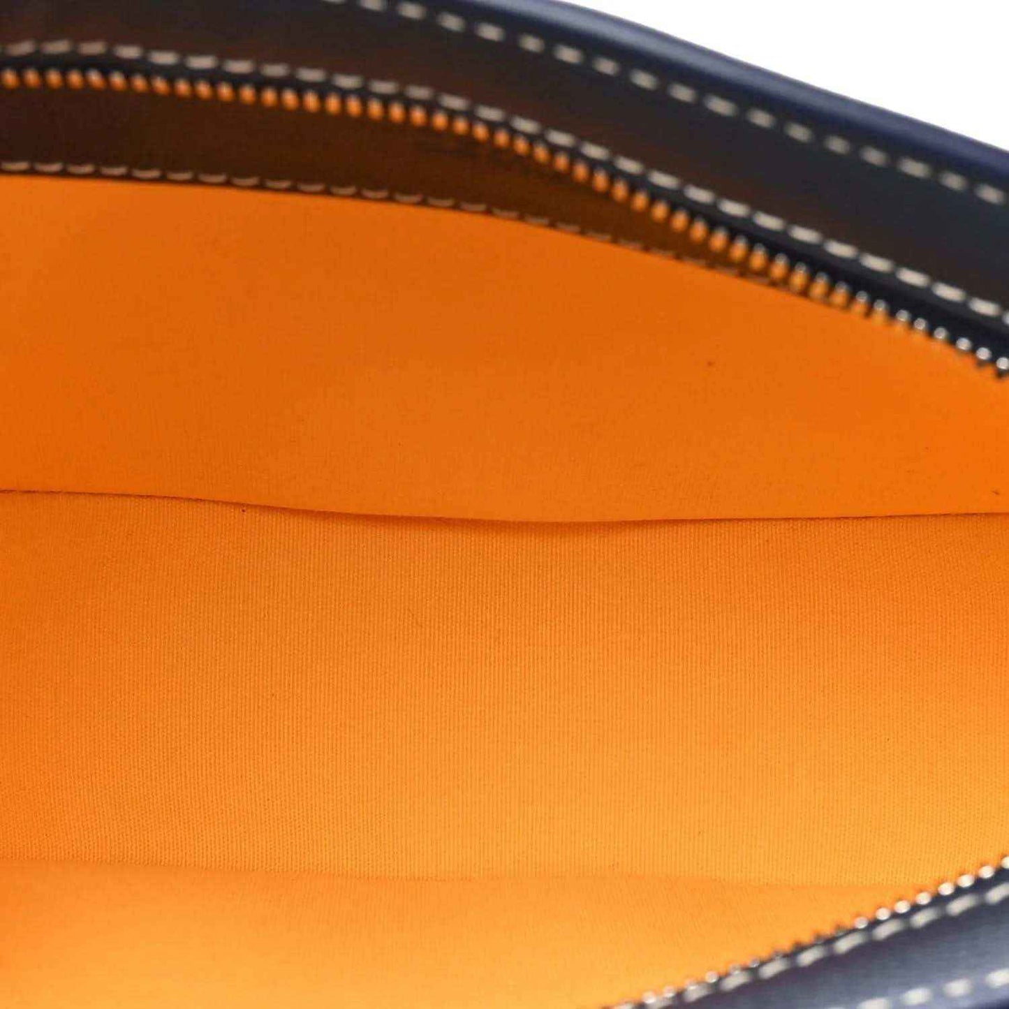 Orange fabric lining inside navy bag, visible zipper edge and stitching