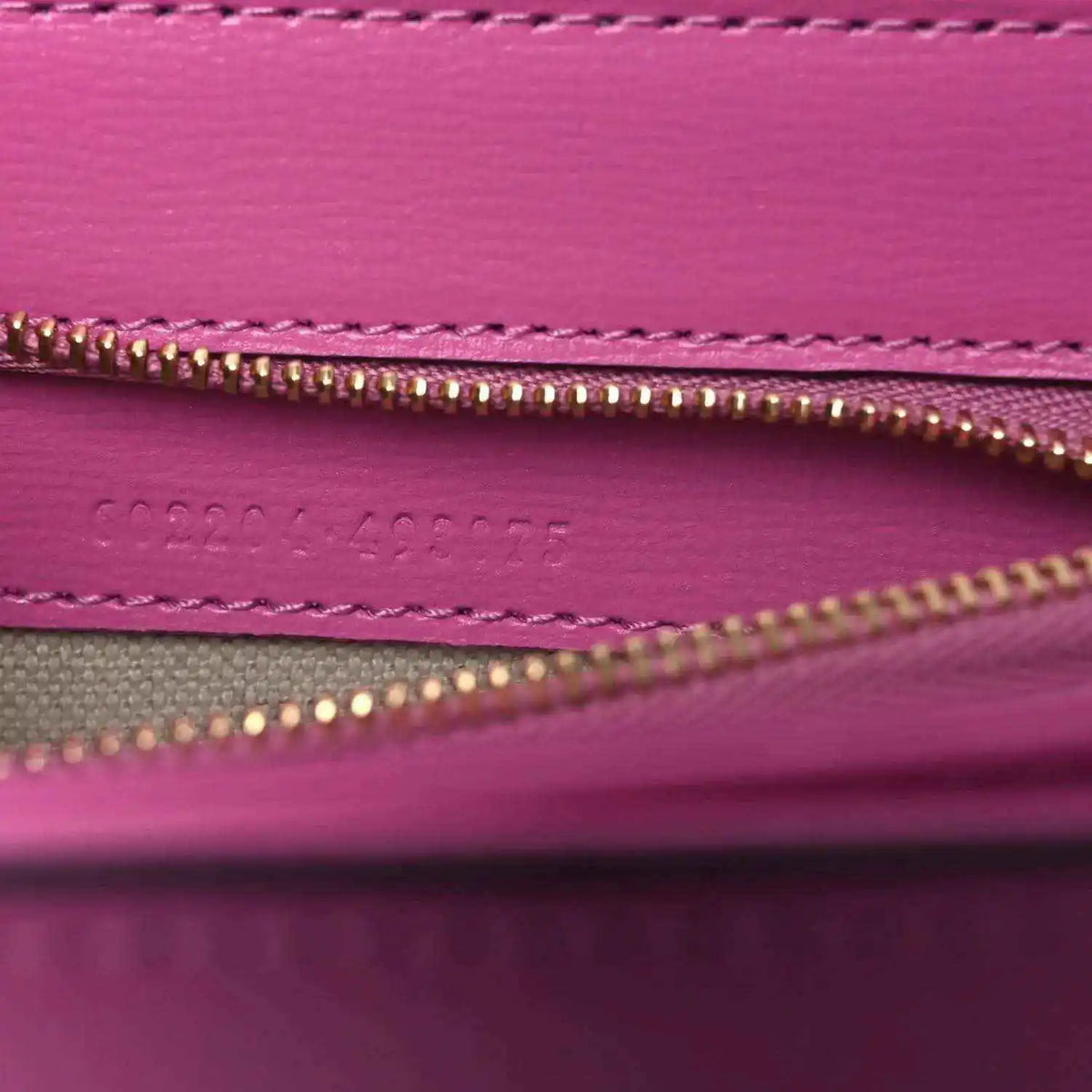 Gucci pink bag interior close-up of gold zipper and stitched inner pocket