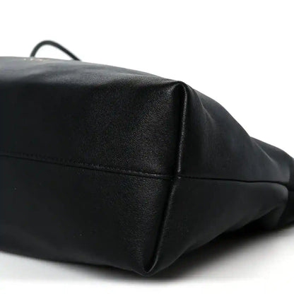 Black leather clutch corner view with top edge seam and subtle pebbled texture.