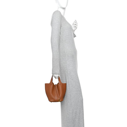 Tan leather Picotin-style bucket bag worn at side view with short handles