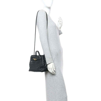 Black woven leather mini shoulder bag worn with a thin crossbody strap