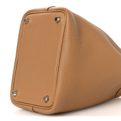 Tan textured leather bucket bag with silver stud corners and curved side profile.