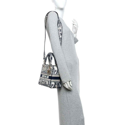 Blue toile de Jouy handbag worn over the shoulder, with gold chain and handles.