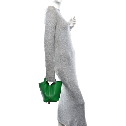 Green leather tote bag with top handles, shown in a side view