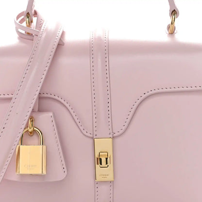 Pastel pink mini top-handle bag close-up with gold padlock charm and front clasp