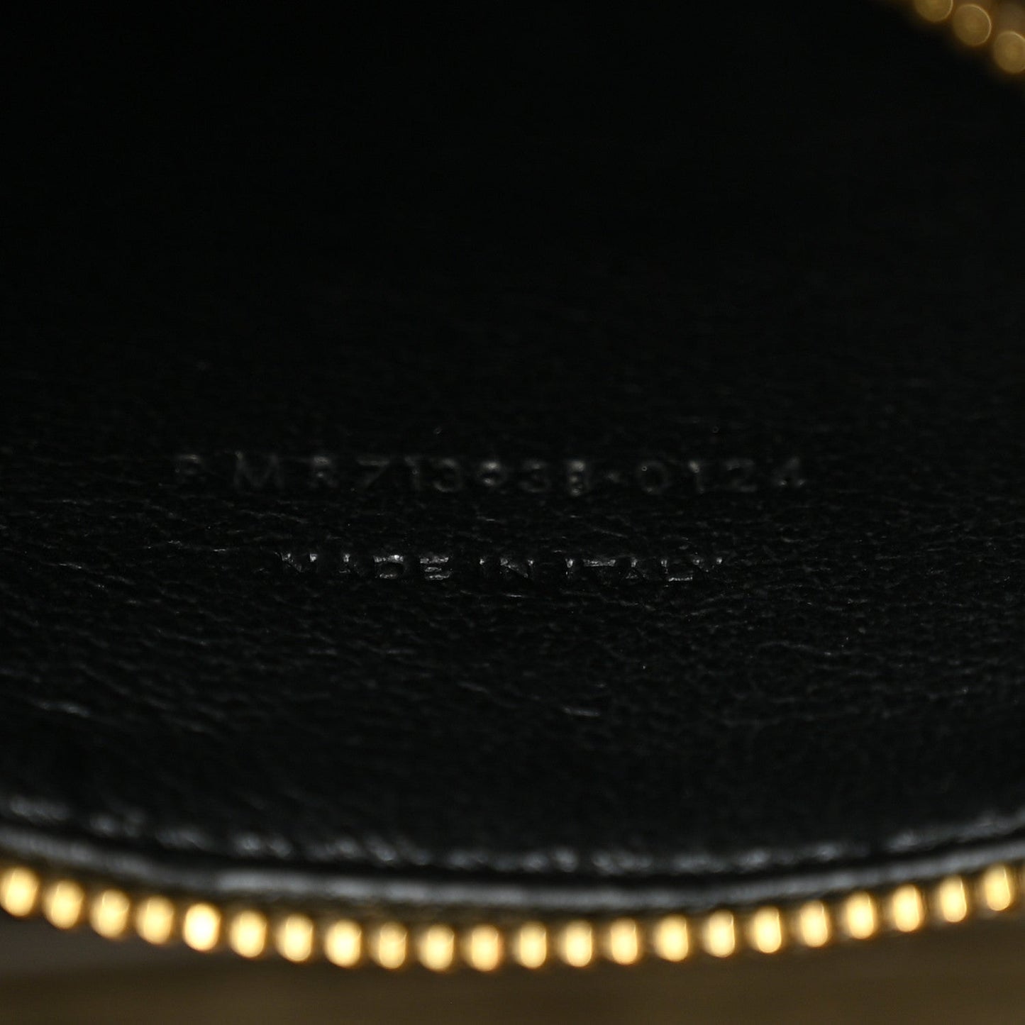 Engraved brand text and code on leather surface with fine stitching.