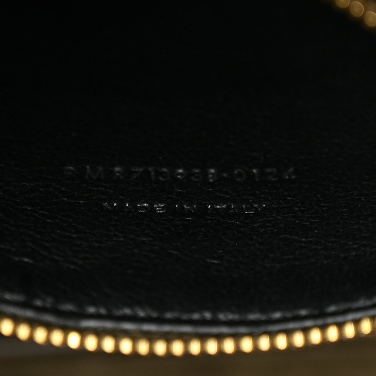 Engraved brand text and code on leather surface with fine stitching.