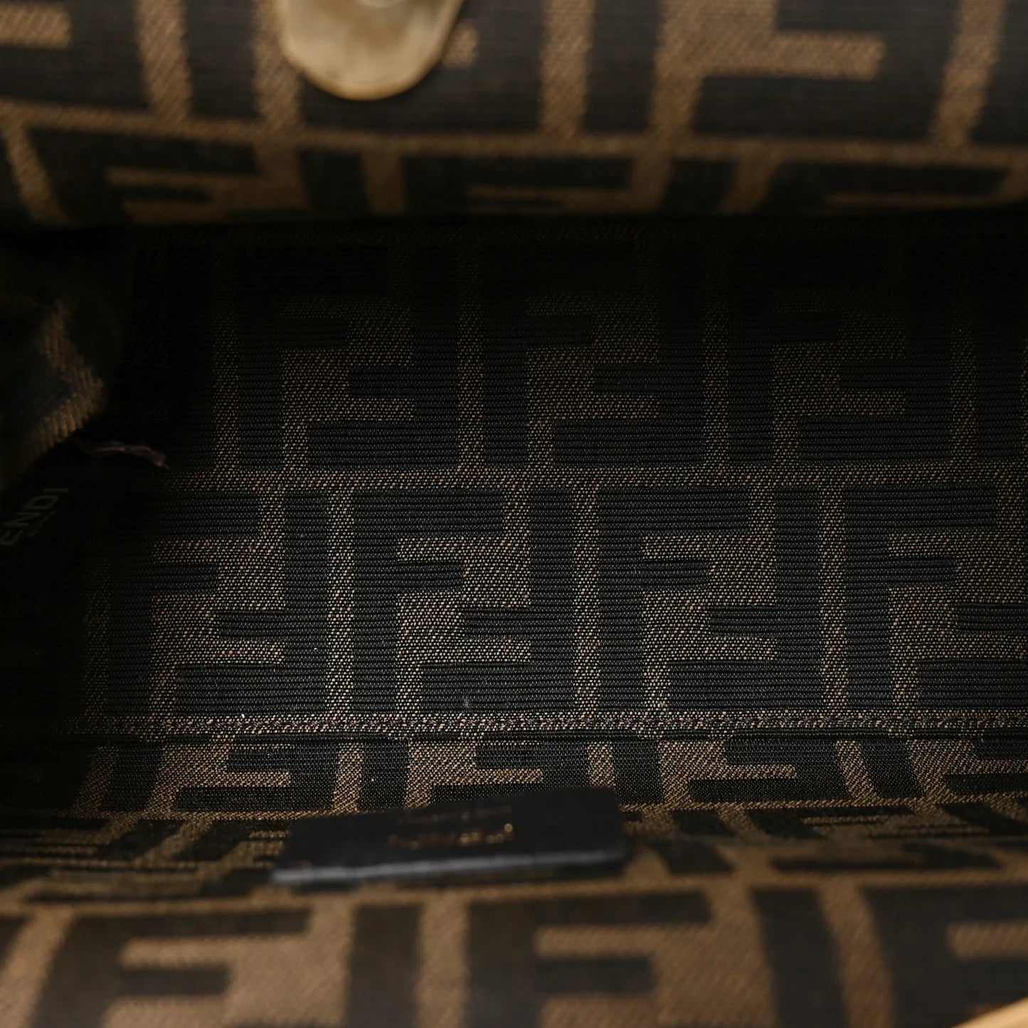 Black leather brand label with FENDI text on small shoulder bag