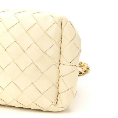 White leather intrecciato clutch texture close-up with gold-tone chain link