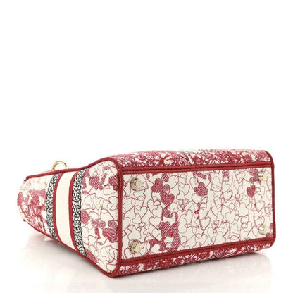 Embroidered canvas bag with red top trim, red-and-white heart pattern, short wrist strap.