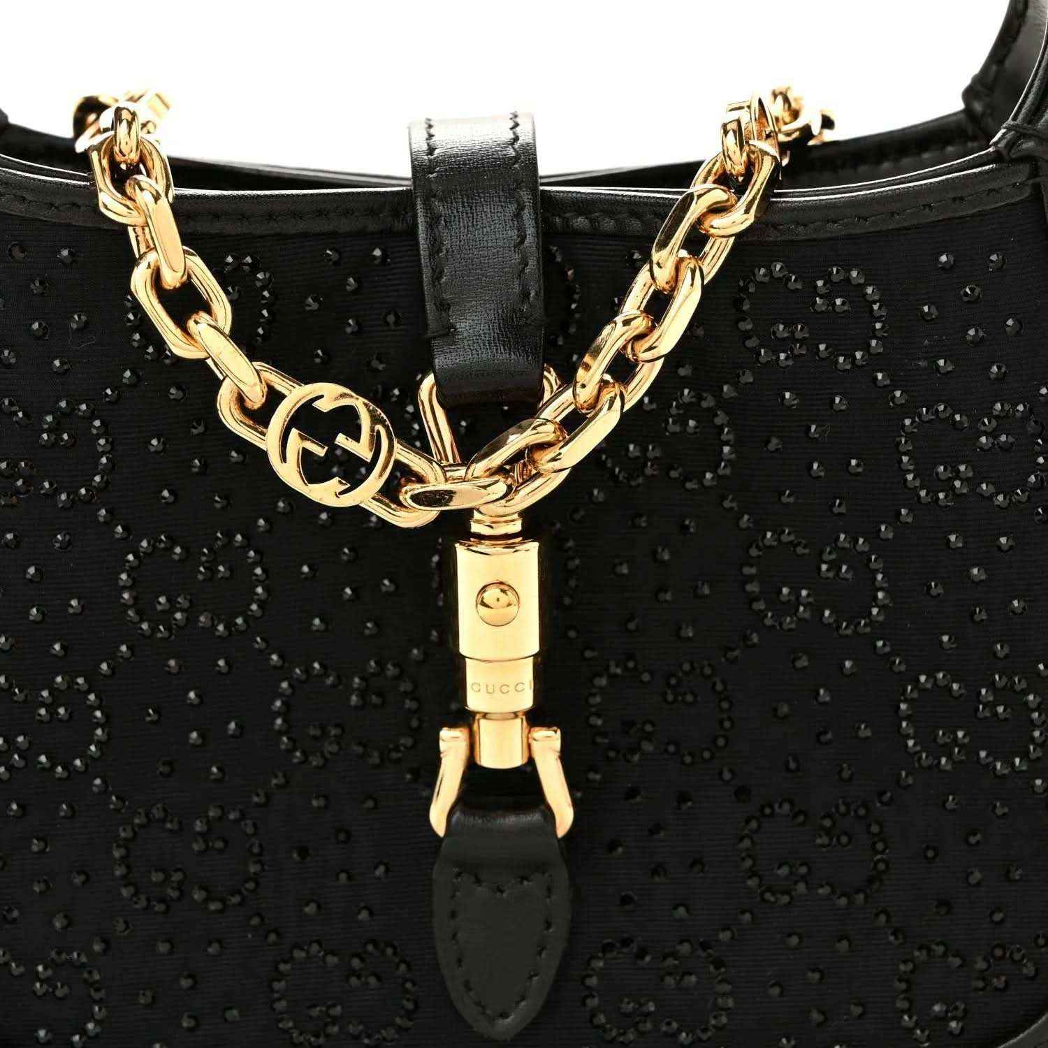 Close-up of black hobo bag front with gold chain detail and clasp hardware.