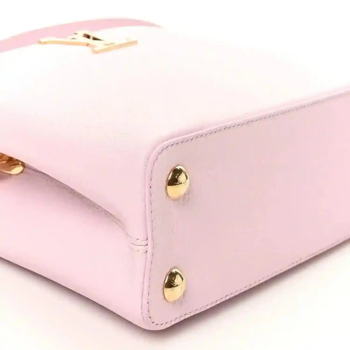 Pink leather handbag corner with gold dome studs and structured edge