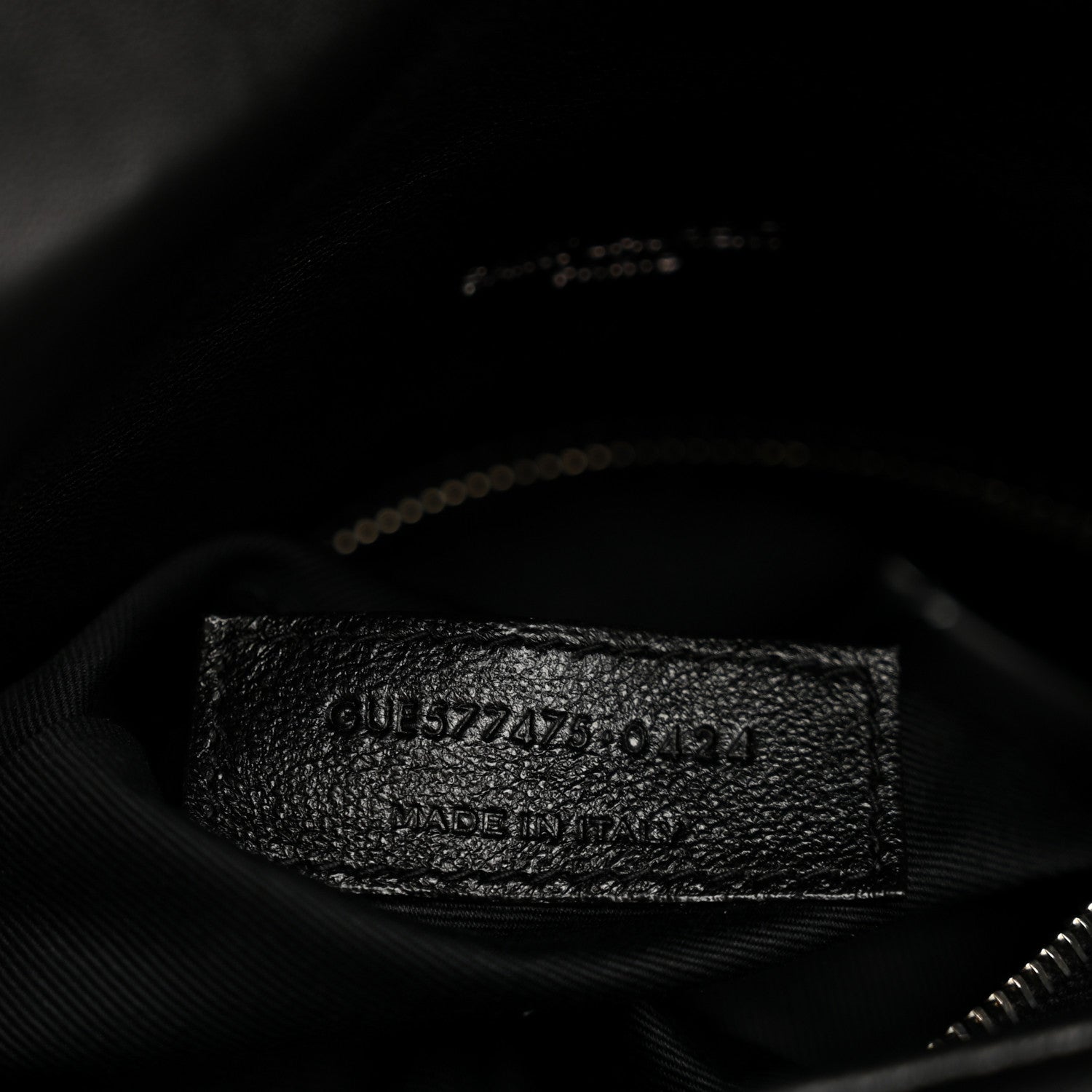 Black fabric inner pocket of quilted satchel with embossed serial-style label