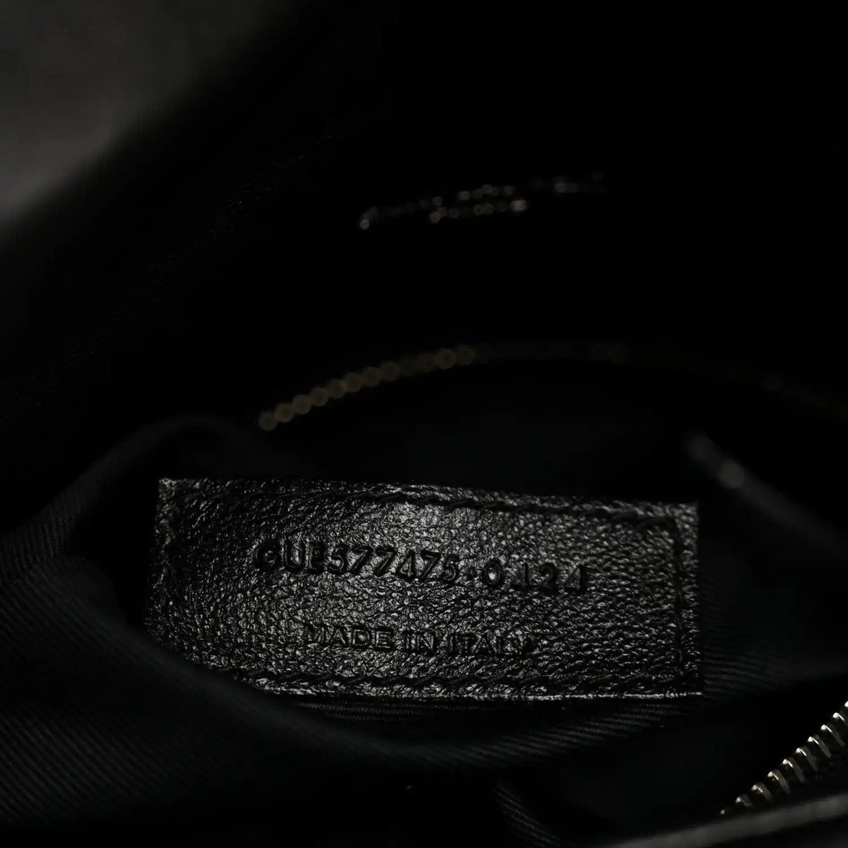 Black fabric inner pocket of quilted satchel with embossed serial-style label