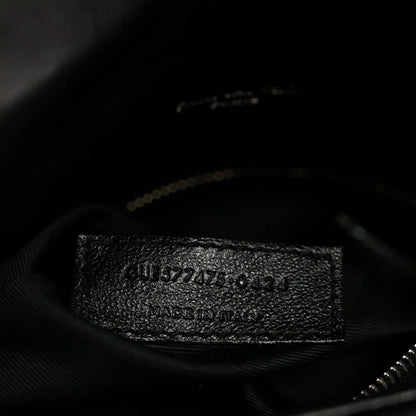 Black fabric inner pocket of quilted satchel with embossed serial-style label