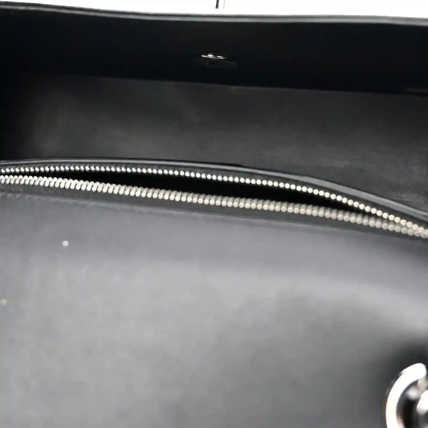 Black bag interior with silver-tone zipper edge and stitched trim.
