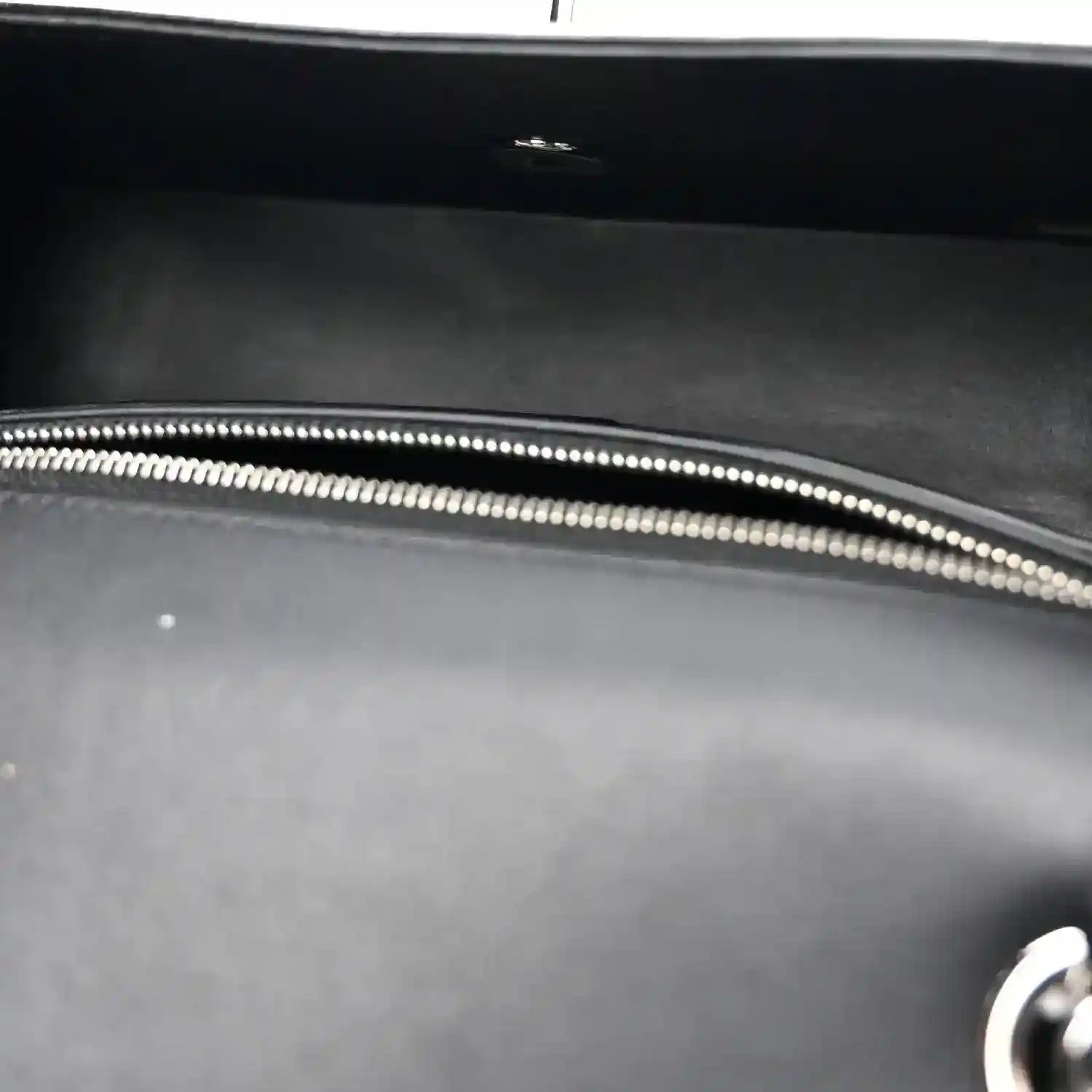 Black bag interior with silver-tone zipper edge and stitched trim.