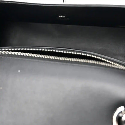 Black bag interior with silver-tone zipper edge and stitched trim.